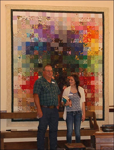 Steve Unruh and his niece Nicolette Unruh stand in front of the Resurrection quilt at the Bergthal Mennonite Church's memorial celebration. Photo by Benita (Unruh) Puck.