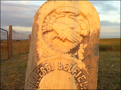 The setting sun illuminates a marker at a cemetery west of Albert along K-96. Photo copyright 2010 by Leon Unruh.