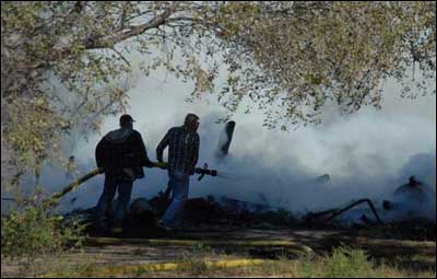 Joe Bilus and Shane Bowman take a hose to the fallen garage. Photo by Jim Dye.